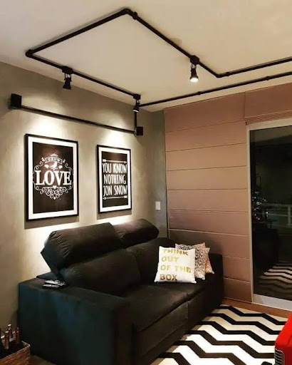 Trilho eletrificado preto com luminárias de led no teto de uma sala.