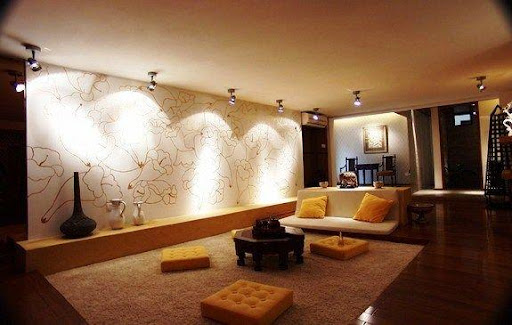 Spots de led direcionados para a parede de uma sala de estar, conectados por um trilho eletrificado, de forma a gerar uma luz indireta